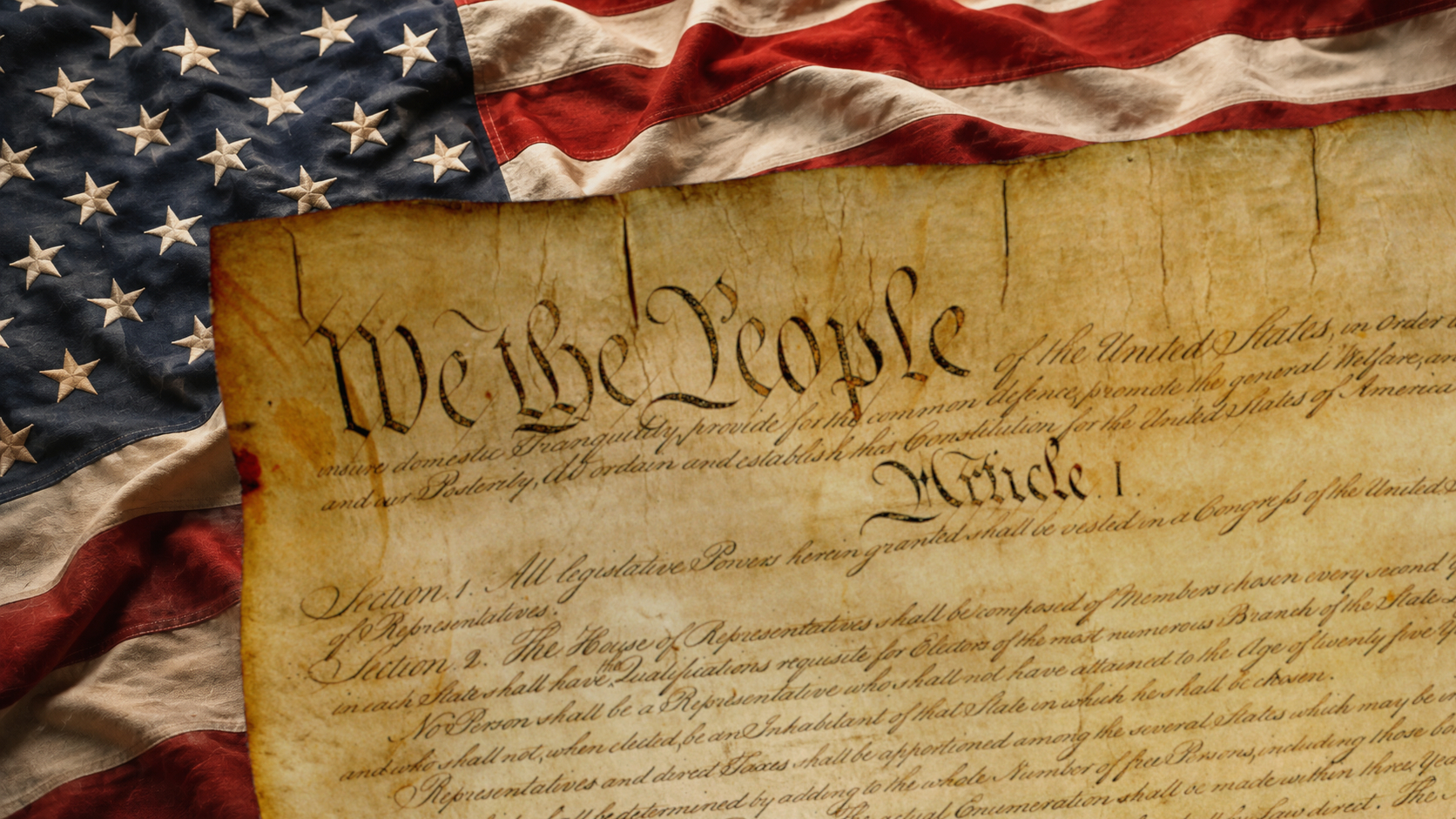 U.S. Constitution resting on an American flag, with “We the People” prominently visible. Constitution image courtesy of the National Archives. Composite by Independent Florida.